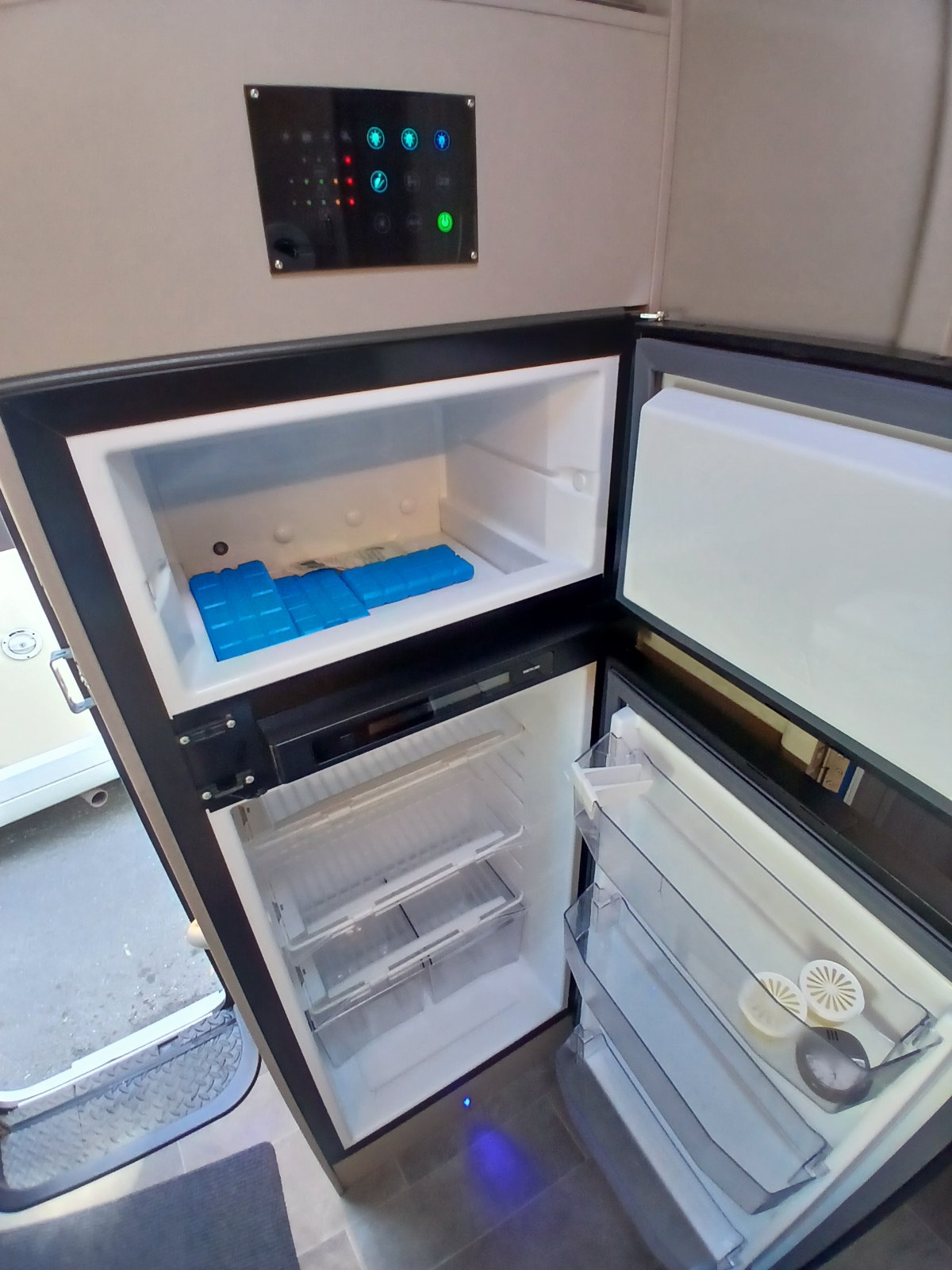 Geöffneter Kühlschrank mit Gefrierfach und Kühlakkus, darüber das Bedienpanel des Aufbaus